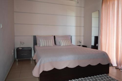 a bedroom with a bed with pink pillows and a mirror at Vasilopoulos Estate in Koroni