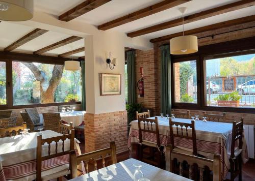 restauracja ze stołami i krzesłami oraz dużymi oknami w obiekcie Hotel rural Los Manzanos w mieście Rascafría