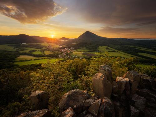 a sunset from the top of a mountain with rocks at Penzion Fara pod Milešovkou in Velemín