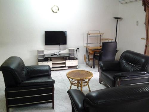 a living room with leather furniture and a flat screen tv at Sophia Hotel in Dar es Salaam