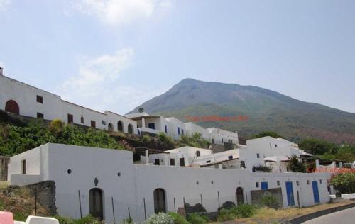 a group of white buildings with a mountain in the background at Ca Balena piccola e grande in Stromboli