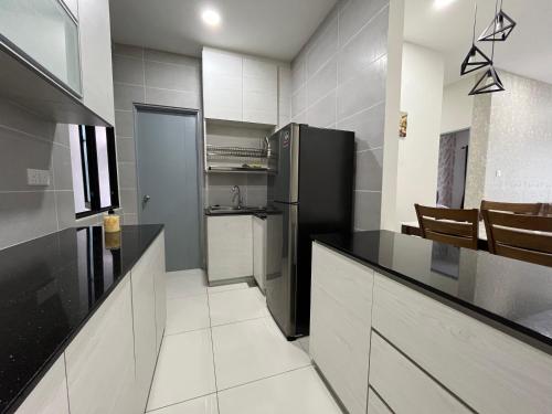 a kitchen with a black refrigerator and white cabinets at Airbnb Homestay P Residence in Kuching