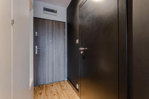 korytarz z czarnymi drzwiami i drewnianą podłogą w obiekcie Apartament Monika w Poznaniu