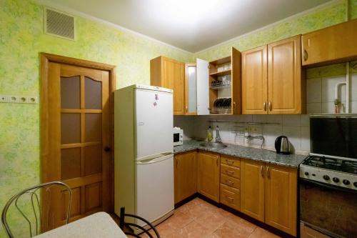 キーウにあるKvartirkoff na Timoshenko 3vのキッチン(白い冷蔵庫、木製キャビネット付)