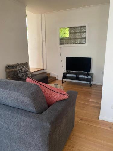 a living room with a couch and a flat screen tv at Hobart Colonial Apartment in Hobart