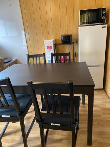 a black table with chairs and a refrigerator at 吉田邸　古民家の落ち着いたお家 in Ichimonji