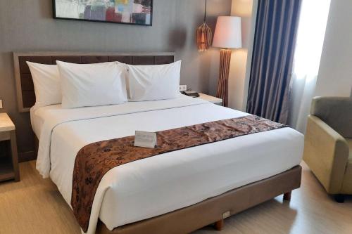 a hotel room with a large bed and a chair at BW Kemayoran Hotel & Convention Powered by Archipelago in Jakarta