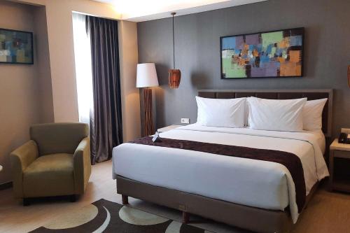 a hotel room with a large bed and a chair at BW Kemayoran Hotel & Convention Powered by Archipelago in Jakarta