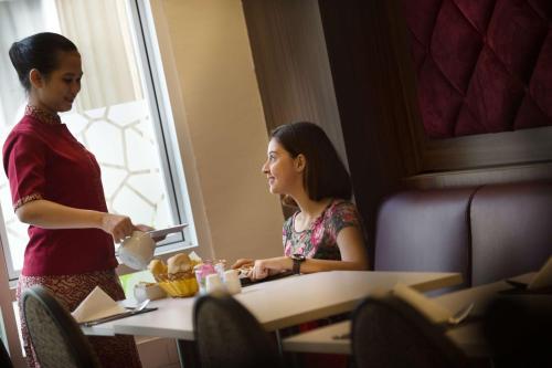 two women sitting at a table in a room at BW Kemayoran Hotel & Convention Powered by Archipelago in Jakarta