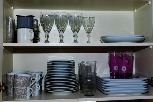 a shelf with dishes and wine glasses and plates at Mukava saunallinen kaksio omalla sisäänkäynnillä ja ilmaisella autopaikalla in Kuopio