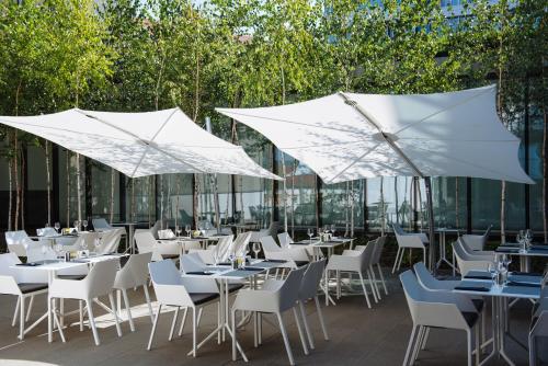 een restaurant met witte tafels, stoelen en parasols bij Villa Csonka by Privo in Târgu-Mureş
