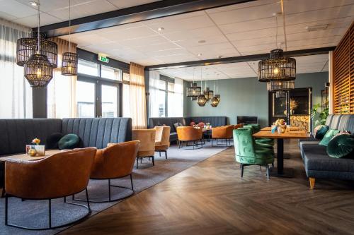 a restaurant with couches and tables and chairs at Hotel Boschrand in De Koog