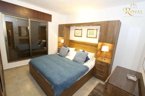 a bedroom with a bed with a wooden head board at Royal Luxury Apartments & Studios in Amman