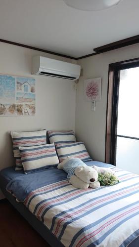 a bed with a teddy bear sitting on top of it at JING HOUSE渋谷ダブルベッド/新宿・渋谷駅近 in Tokyo