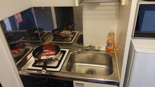 a kitchen with a sink and a stove with pots and pans at JING HOUSE渋谷ダブルベッド/新宿・渋谷駅近 in Tokyo