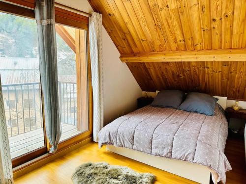 a bedroom with a bed and a large window at Le Coucou - Grand chalet - Parking - WIFI - ALLOS - 10adul+2enf in Allos