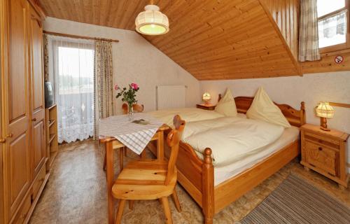 Schlafzimmer mit einem Bett, einem Tisch und einem Fenster in der Unterkunft Pension Wiesengrund in Neuschönau