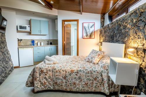1 dormitorio con cama y pared de piedra en Estancia Dacil en La Orotava