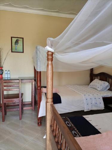 1 dormitorio con cama con dosel y escritorio en Pross Residence en Masindi