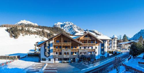 a hotel in the snow with mountains in the background at Residence Rautal B&B ***S in San Vigilio Di Marebbe