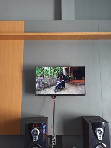 a tv hanging on a wall with a person on a motorcycle at Ganjar Homestay in Sentool