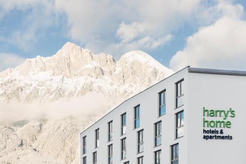 een wit gebouw met een berg op de achtergrond bij harry's home Telfs hotel & apartments in Telfs