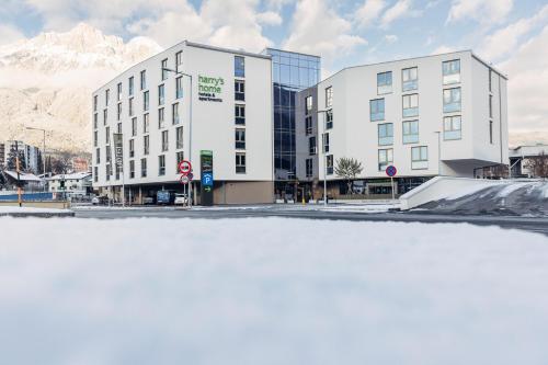 a snow covered street with a building and mountains at harry's home Telfs hotel & apartments in Telfs