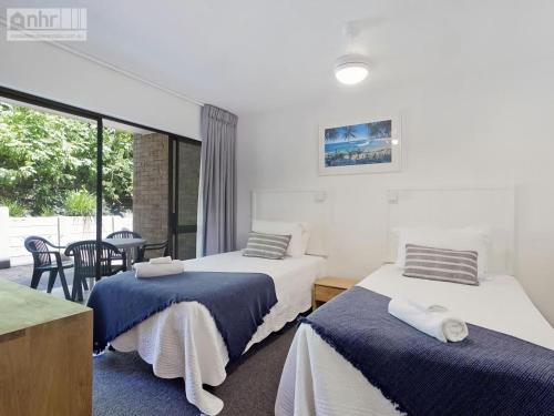 a room with two beds and a table and a window at Sundown Lodge 1 Edgar Bennett Avenue 14 in Noosa Heads