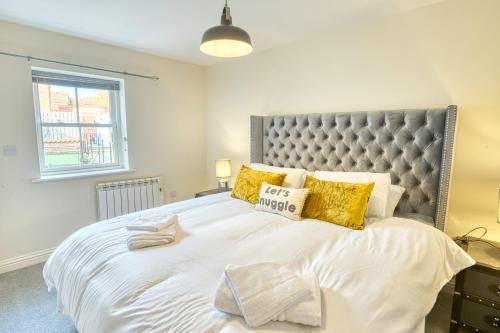 um quarto com uma grande cama branca com almofadas amarelas em Pass the Keys Cosy flat in the Town Centre em Sleaford