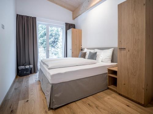 Un dormitorio con una cama grande y una ventana en All-Suite Resort Paznaun en Galtür