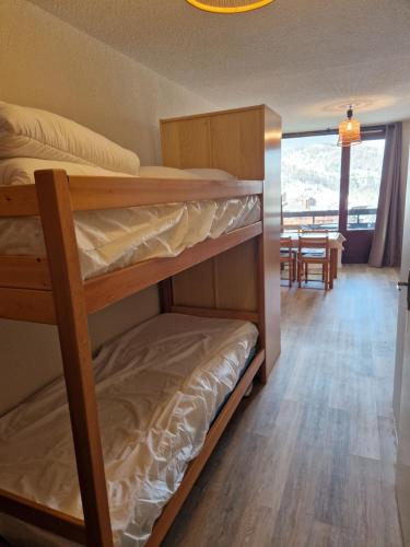 ein Schlafzimmer mit Etagenbetten und ein Esszimmer mit einem Tisch in der Unterkunft Boost Your Immo Risoul Le Diamant 823 in Risoul