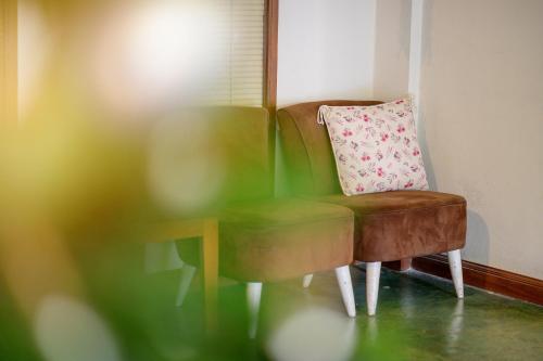 a brown chair with a pillow next to a green chair at Estia Chiangmai in Chiang Mai