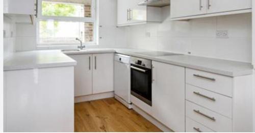 cocina blanca con fregadero y fogones en City Riverview 1/2 Bedroom Apartment en Londres