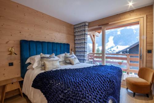 a bedroom with a blue bed and a window at Chalet Tilly in Morzine