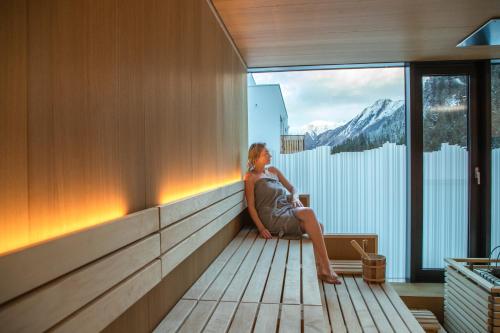 a woman sitting on a balcony looking out a window at All-Suite Resort Paznaun in Galtür