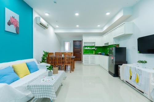 ein Wohnzimmer mit einem weißen Sofa und einer Küche in der Unterkunft Gold Sea Apartment Vung Tau-The Palm Sea View in Vũng Tàu