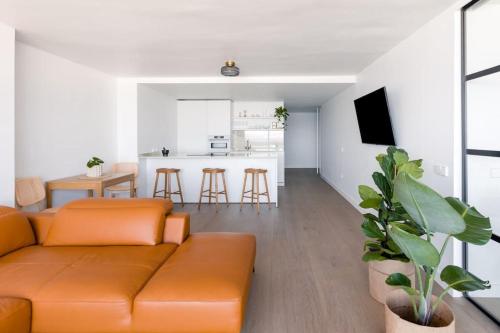 a living room with an orange couch and a kitchen at Diamond Suite Bajamar in Bajamar