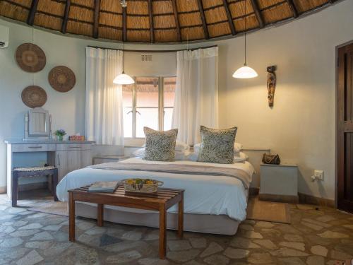 ein Schlafzimmer mit einem großen Bett und einem Tisch in der Unterkunft Mohlabetsi Safari Lodge in Hoedspruit