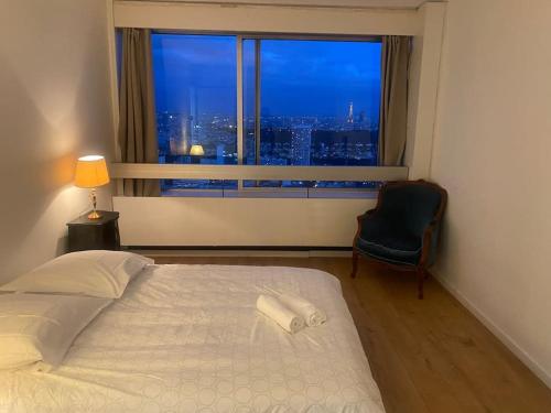 a bedroom with a large window with a bed and a chair at Tour Défense 2000 Magnifique Appartement in Puteaux
