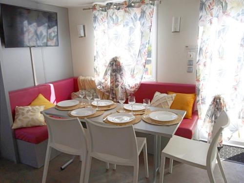 a dining room with a table and a red couch at Mobil home-Les Lins Bleus in Biville-sur-Mer
