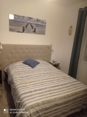 1 cama en un dormitorio con una foto en la pared en La maison du midi, en Cérans-Foulletourte