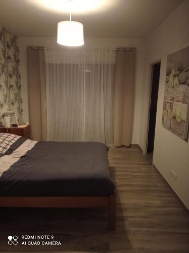 1 dormitorio con cama y ventana grande en La maison du midi, en Cérans-Foulletourte