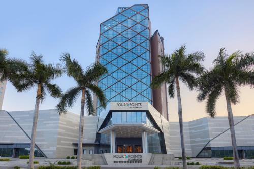 een hoog gebouw met palmbomen ervoor bij Four Points by Sheraton Shenzhen Bao'an in Shenzhen