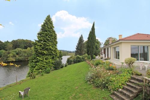 a house on a hill next to a river at Dominant l'etang in Compreignac