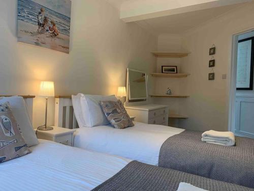 a bedroom with two beds and a television in it at Crow’s Nest, Central New Forest coastal village beach apartment in Milford on Sea