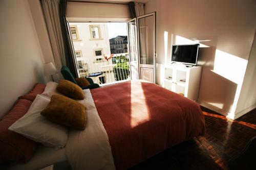 a bedroom with a bed and a balcony with a television at Oleiros Rooms City Center in Coimbra