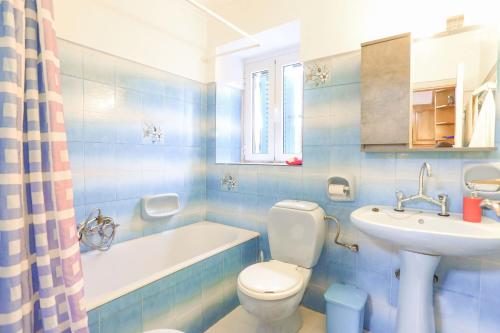 a blue tiled bathroom with a toilet and a sink at Archontiko Aliki in Sgourádes