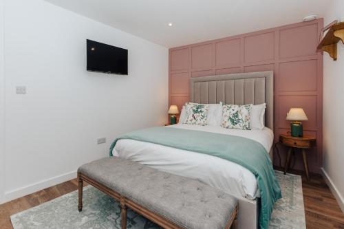 een slaapkamer met een groot bed en een televisie bij Stable Mews, Prestbury Cheltenham in Southam