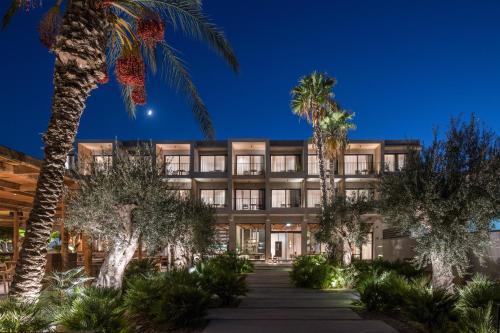 an exterior view of a building with palm trees at Lindos Aqua Terra in Líndos