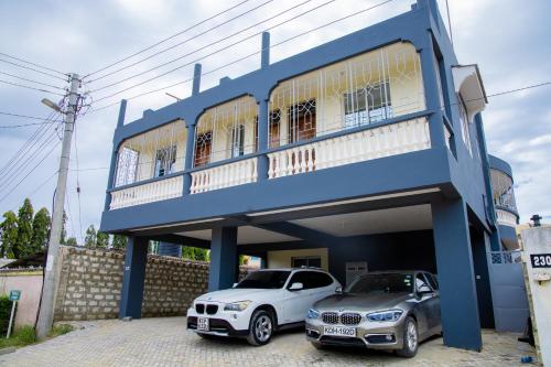 dois carros estacionados em frente a um edifício azul em Royal Haven A3 Spacious 1Br Apartment 10min drive to beach hosts upto 4 guests WiFi - Netflix, 10min drive to beach em Mombaça